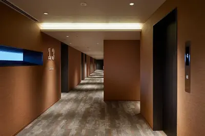 a corridor of a hotel hallway with brown walls and floors at OMO5 Tokyo Otsuka by Hoshino Resorts in Tokyo