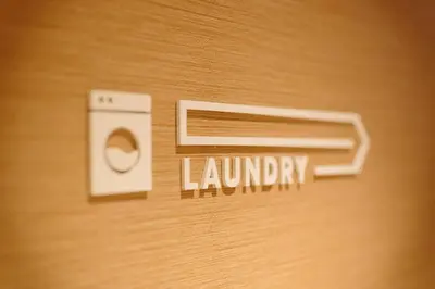 a sign that says laundry on a wooden wall at OMO5 Tokyo Otsuka by Hoshino Resorts in Tokyo