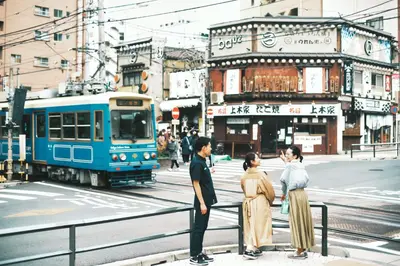 a group of people standing on a sidewalk near a train at OMO5 Tokyo Otsuka by Hoshino Resorts in Tokyo