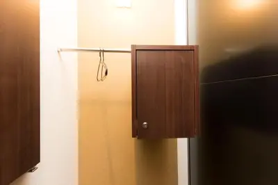 a wooden cabinet in the corner of a bathroom at Ryoma Ikebukuro in Tokyo