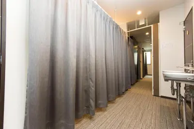 a row of gray shower curtains in a bathroom at Ryoma Ikebukuro in Tokyo