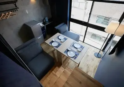 a living room with a table and a blue couch at Arcsens Tokyo in Tokyo