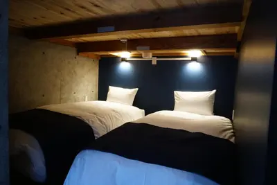 two beds in a room with lights on the wall at Arcsens Tokyo in Tokyo