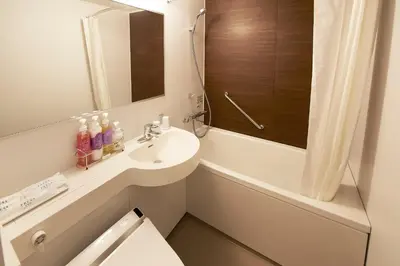 a white bathroom with a sink and a mirror at Sotetsu Fresa Inn Tokyo Kanda in Tokyo