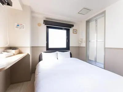 a bedroom with a white bed and a window at Chang Tee Hotel Ikebukuro in Tokyo
