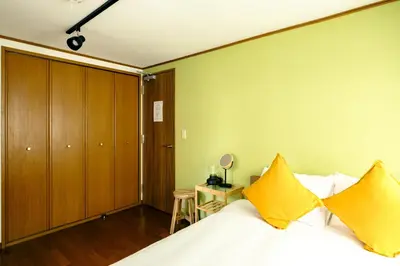 a bedroom with a bed with yellow pillows at Ikken House in Tokyo