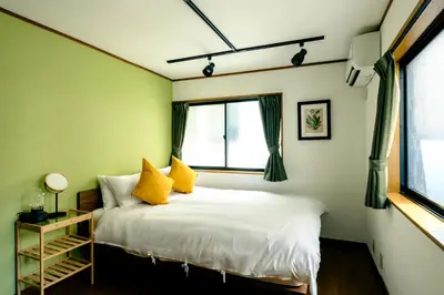 a bedroom with a bed with yellow pillows and a window at Ikken House in Tokyo