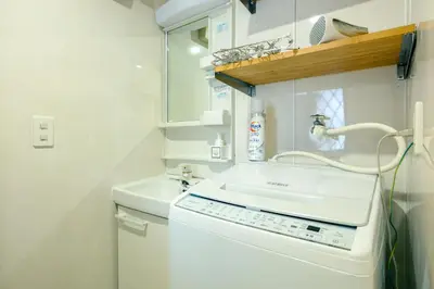 a small white bathroom with a sink and a mirror at Ikken House in Tokyo