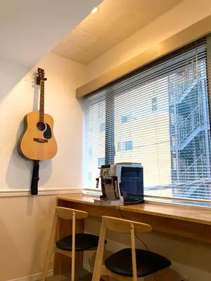 a guitar hanging on a wall next to a desk with a computer at bnb+ Shinbashi in Tokyo