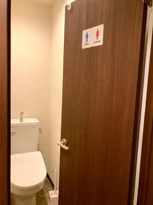 a bathroom with a toilet and a door with a sign on it at bnb+ Shinbashi in Tokyo