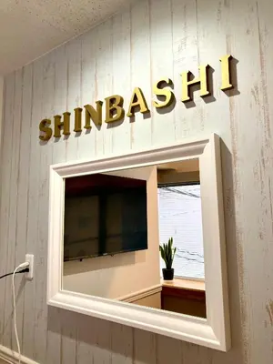 a sign for a shimash sign on a wall at bnb+ Shinbashi in Tokyo