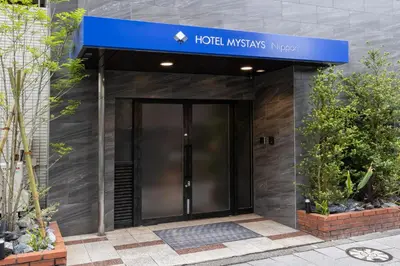 a hotel entrance with a blue sign on a building at HOTEL MYSTAYS Nippori in Tokyo