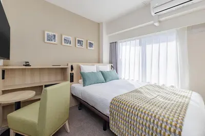 a bedroom with a bed and a desk and a chair at HOTEL MYSTAYS Nippori in Tokyo