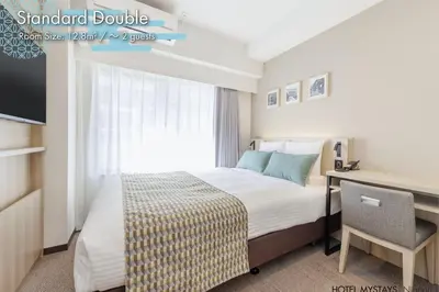 a hotel room with a bed and a desk with a computer at HOTEL MYSTAYS Nippori in Tokyo