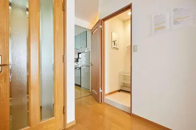 a hallway with a door leading to a kitchen with a refrigerator at F1-Upmarket Huose in Shinjuku in Tokyo