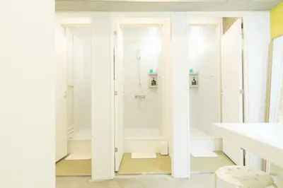 a white bathroom with a shower and a sink at hostel DEN in Tokyo
