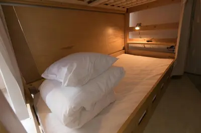 a bed with white sheets and pillows in a room at hostel DEN in Tokyo