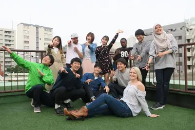 a group of people posing for a picture on a balcony at hostel DEN in Tokyo