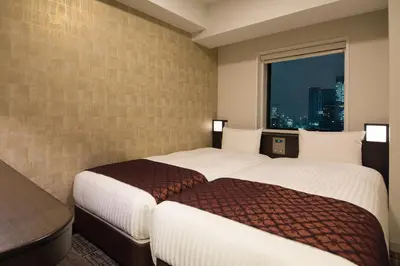 two beds in a hotel room with a window at Toshi Center Hotel in Tokyo