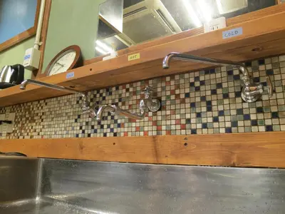 a kitchen with a sink and two faucets at No Borders Hostel in Tokyo