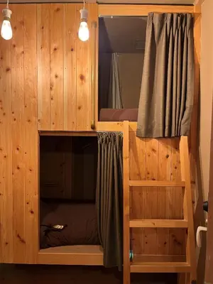 a bunk bed in a wooden cabin with a mirror at No Borders Hostel in Tokyo