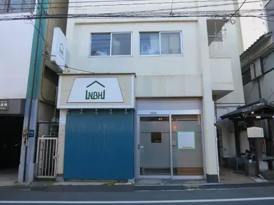 a building with a blue door on a street at No Borders Hostel in Tokyo