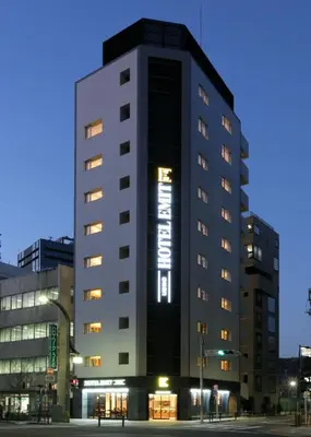 a tall black building with a sign on it at Hotel Emit Ueno in Tokyo