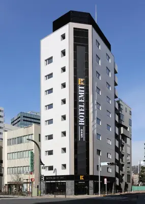 a tall white building with a sign on it at Hotel Emit Ueno in Tokyo