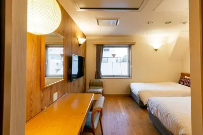 a hotel room with two beds and a table at Hotel Toms in Tokyo