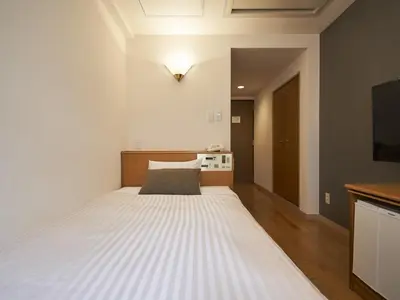 a bedroom with a large white bed in a room at Hotel Toms in Tokyo