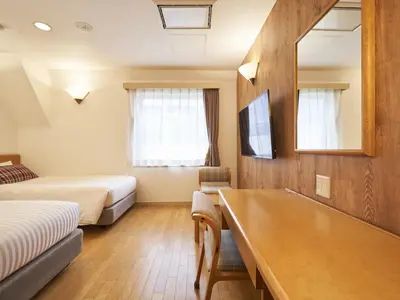 a hotel room with two beds and a bathtub at Hotel Toms in Tokyo