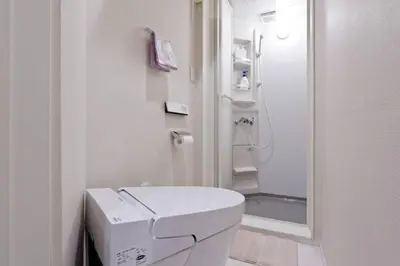 a white bathroom with a toilet and a shower at House In Azabu in Tokyo