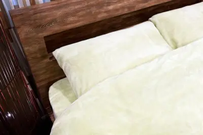 a bed with white sheets and a wooden head board at House In Azabu in Tokyo