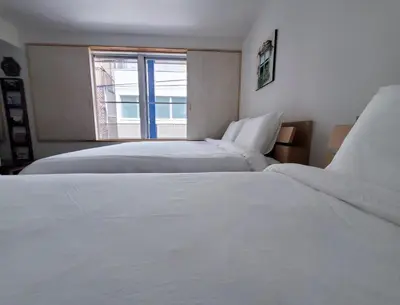 two white beds in a room with a window at Rooms in Tokyo