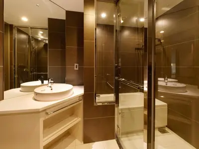 a bathroom with two sinks and a glass shower at Hotel Keihan Tsukiji Ginza Grande in Tokyo