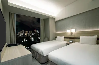 a hotel room with two beds and a window at Hotel Keihan Tsukiji Ginza Grande in Tokyo