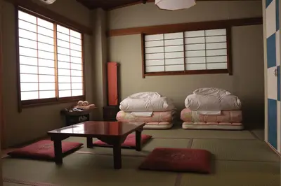 a living room with a table and some pillows at Ito Ryokan in Tokyo