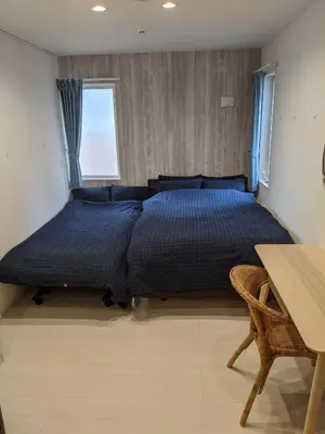 a bedroom with a large bed with a blue comforter at Port House Shibuya in Tokyo