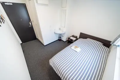 a small room with a bed and a sink at Port House Shibuya in Tokyo