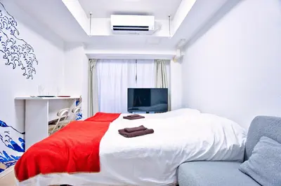 a bedroom with a bed with a red blanket and a couch at Square Shibuya 407 in Tokyo