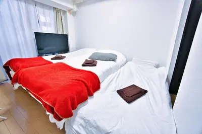 two beds in a room with red and white sheets at Square Shibuya 407 in Tokyo