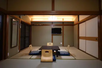 a room with a table and chairs and a tv at Ryokan Sansuiso in Tokyo