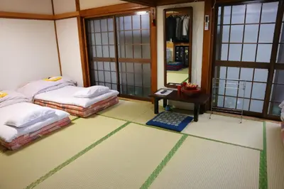 a room with two beds and a table and a mirror at Ryokan Sansuiso in Tokyo