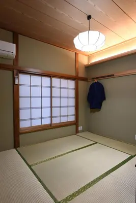 a room with a room with a bed and a light at Ryokan Sansuiso in Tokyo