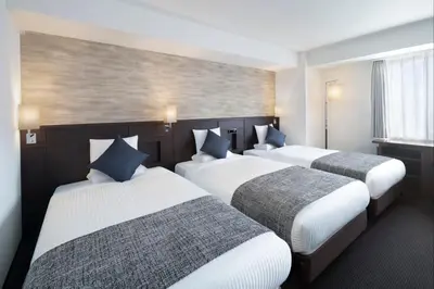 a hotel room with three beds and a window at ART HOTEL Nippori Lungwood in Tokyo