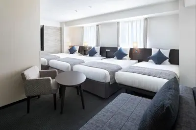 a room with four beds and a table and chairs at ART HOTEL Nippori Lungwood in Tokyo