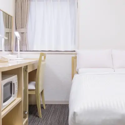 a hotel room with a bed and a desk with a microwave at HOTEL MYSTAYS Higashi Ikebukuro in Tokyo