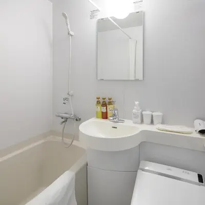 a white bathroom with a sink and a bath tub at HOTEL MYSTAYS Higashi Ikebukuro in Tokyo