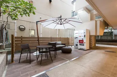 a patio with a table and chairs and an umbrella at HOTEL MYSTAYS Gotanda in Tokyo