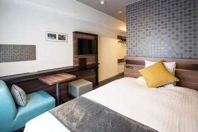 a bedroom with a bed and a chair and a television at HOTEL MYSTAYS Gotanda in Tokyo